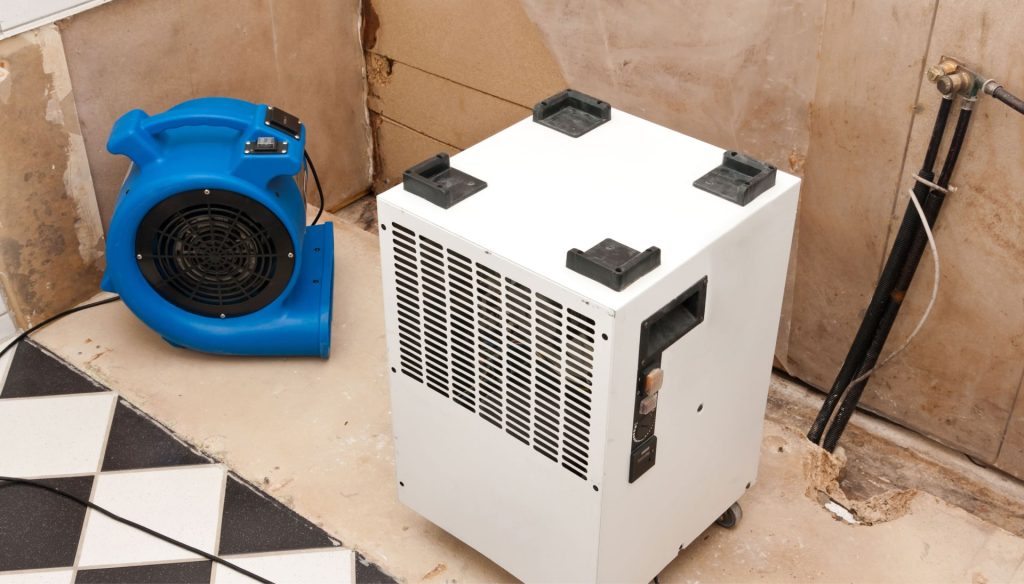 A dehumidifier and fan are set-up in a room to remove moisture during water damage cleanup in a home in Modesto, CA.